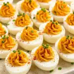 devilled eggs recipe with paprika and chives on a white platter