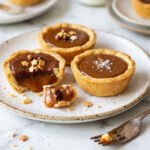 caramel tarts with glossy caramel filling and sea salt flakes on a white plate